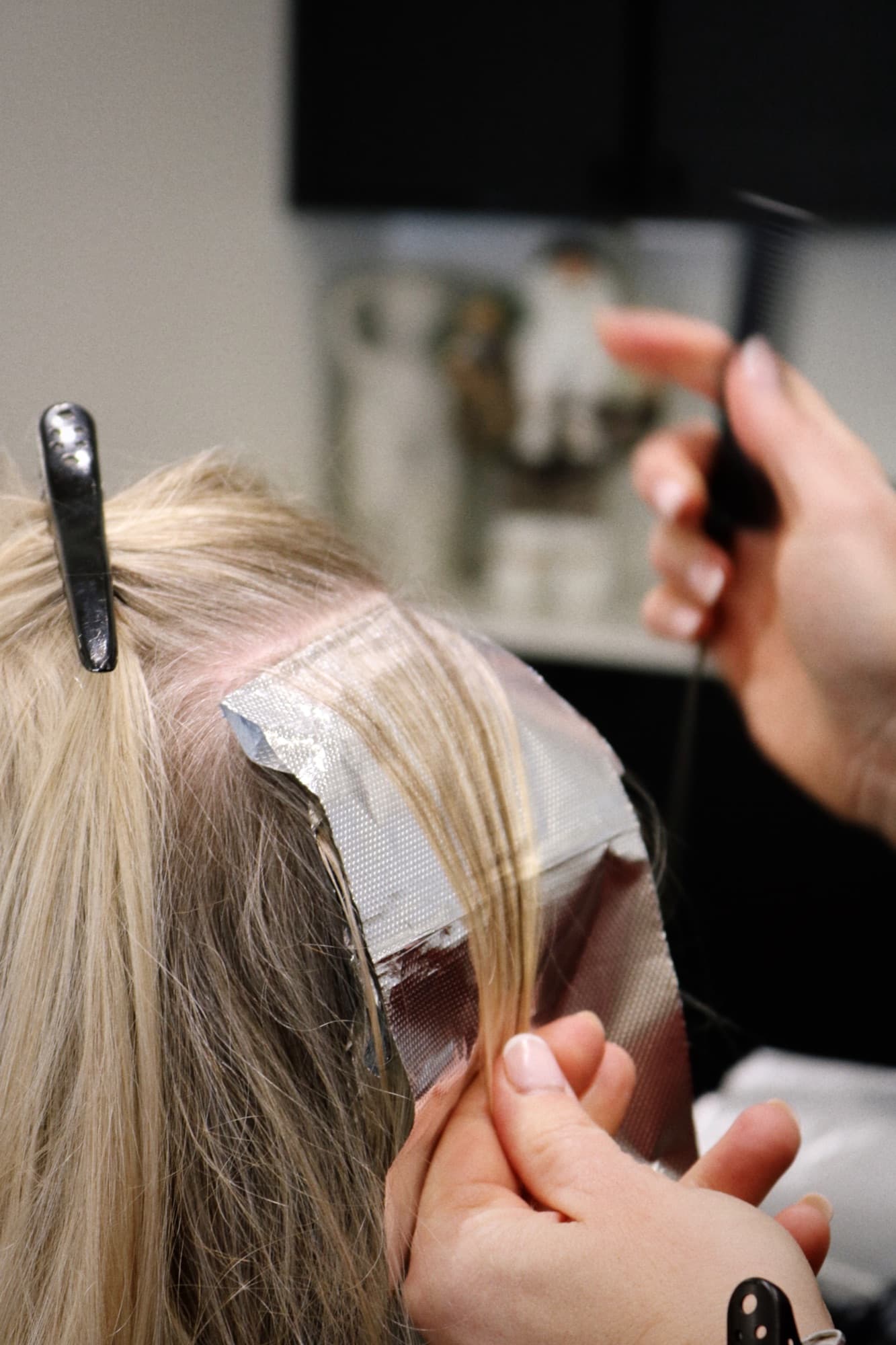 Stylist applying foil highlights to blonde hair